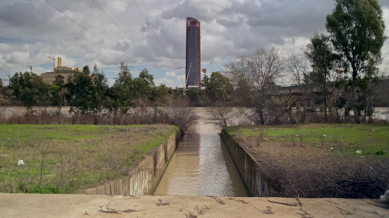 Fiume Guadalquivir a Siviglia che straripa, mostrando il Canale di Alfonso XIII e il grattacielo Torre Sevilla.