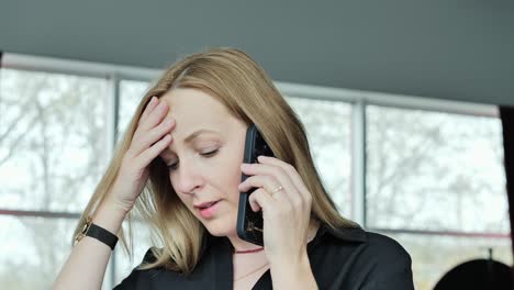close up of business woman talking on phone looking tense, bright office window