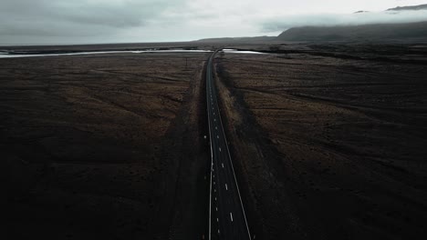 epic flying over empty road in mossy volcanic stone nature, epic moody dark landscape distant view iceland