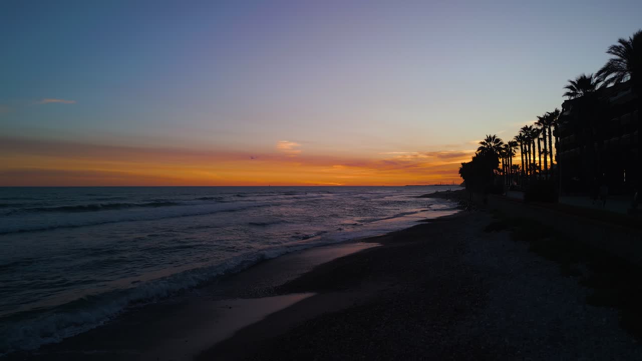 Bellissimo tramonto su spiaggia oceanica con palme ed edifici costieri