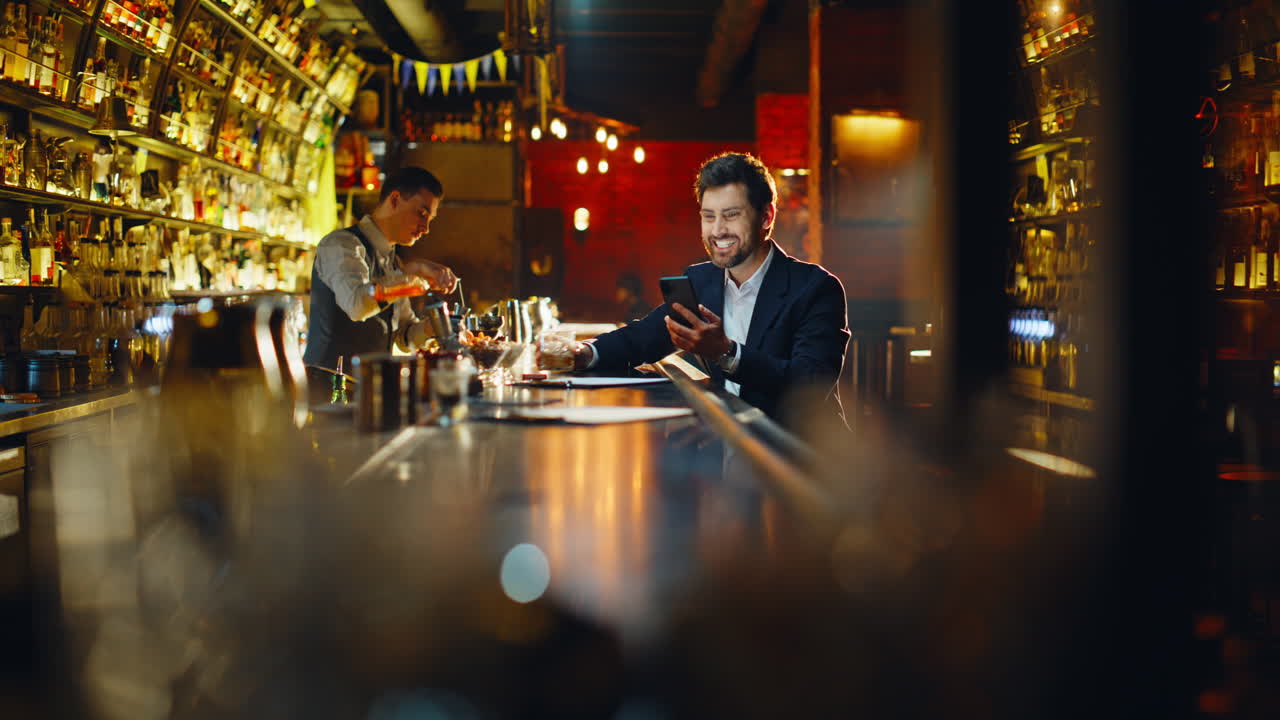 Successful man rejoicing achievement looking cellphone celebrating in night pub