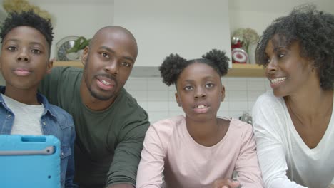 joyful family talking directly into webcam during video call