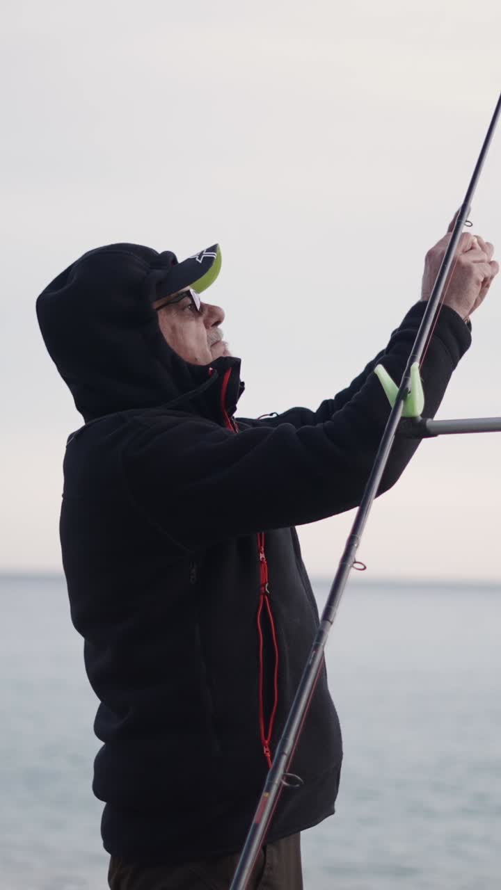 Fisherman preparing his fishing rod by the sea