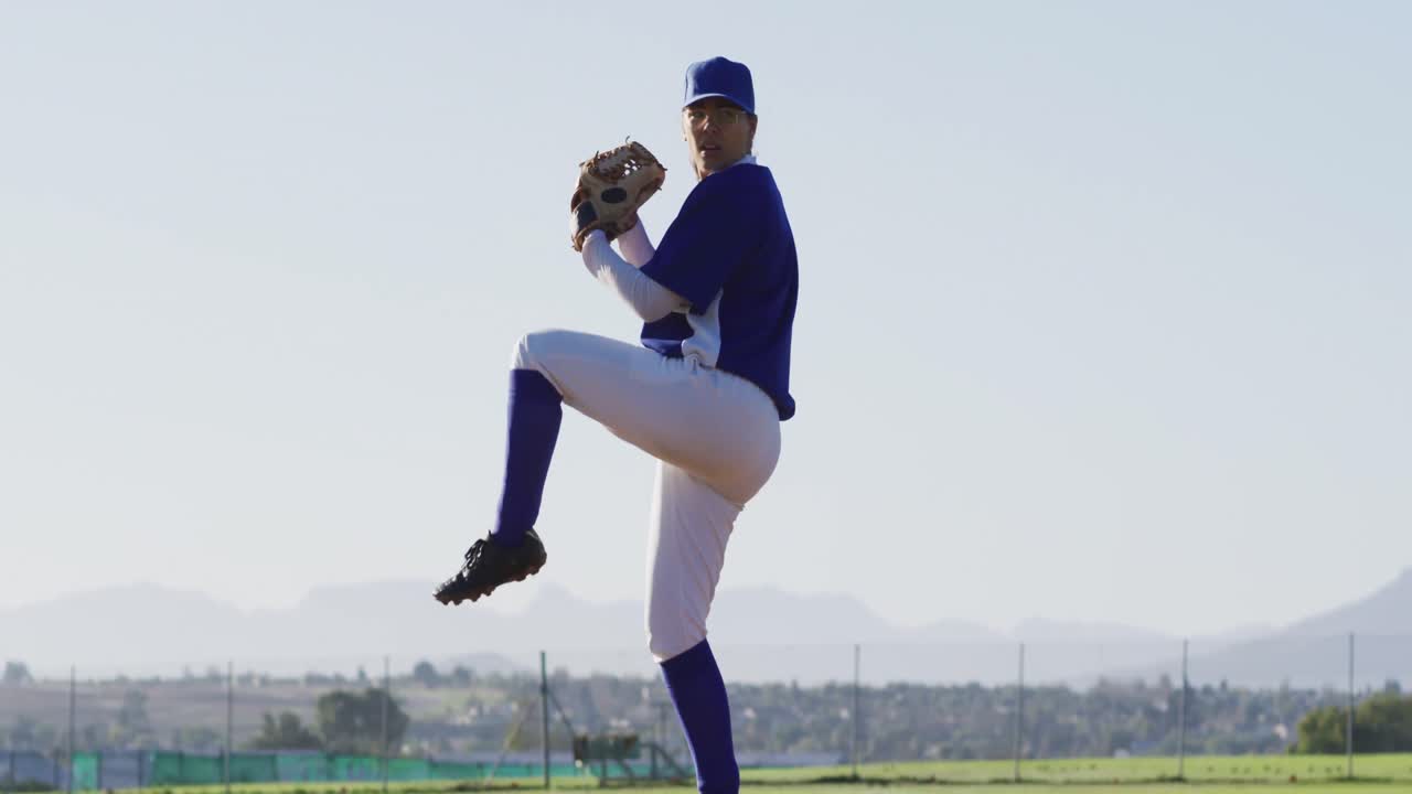 Giocatrice di baseball caucasica con gli occhiali che lancia la palla su un campo da baseball.
