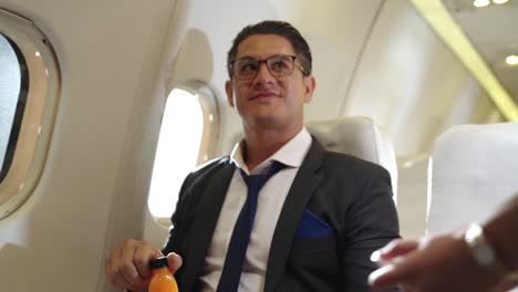 businessman have orange juice served by an air hostess in airplane