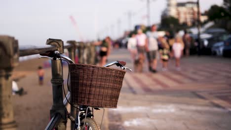 vintage bicycle with basket parked on the sidewalk during sunset, people walking behind