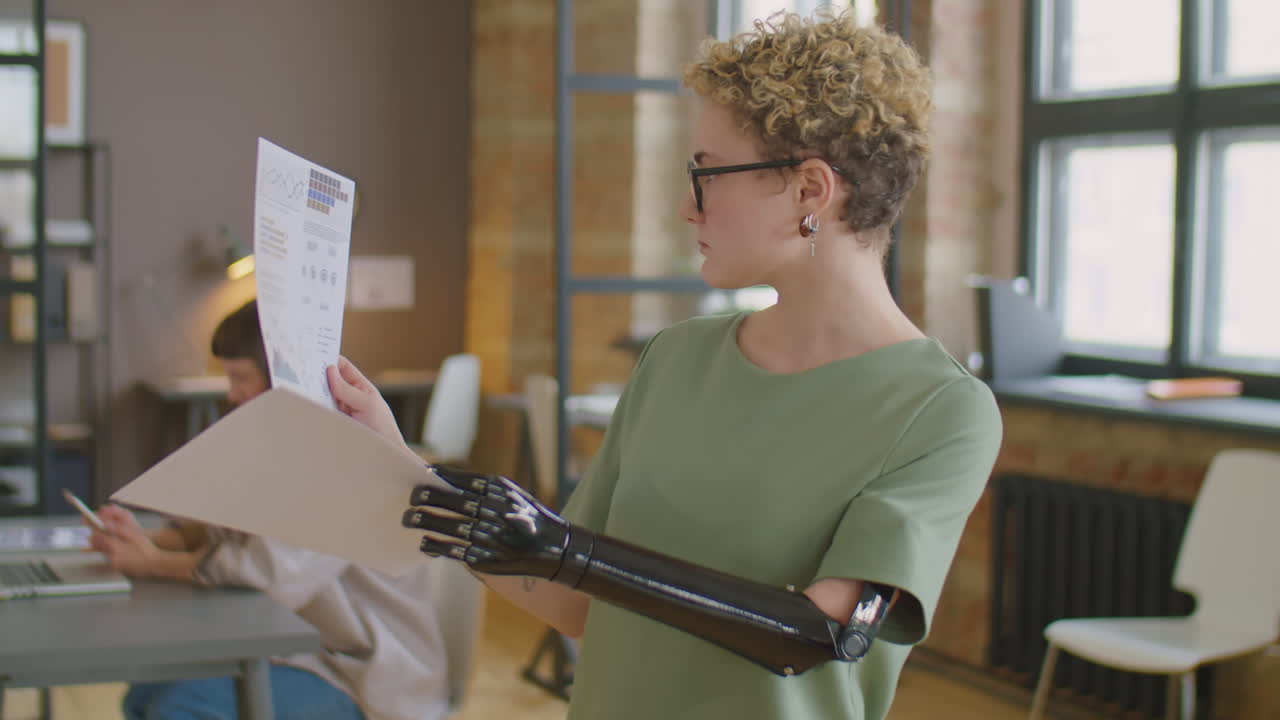 Businesswoman with Prosthetic Arm Checking Papers in Office