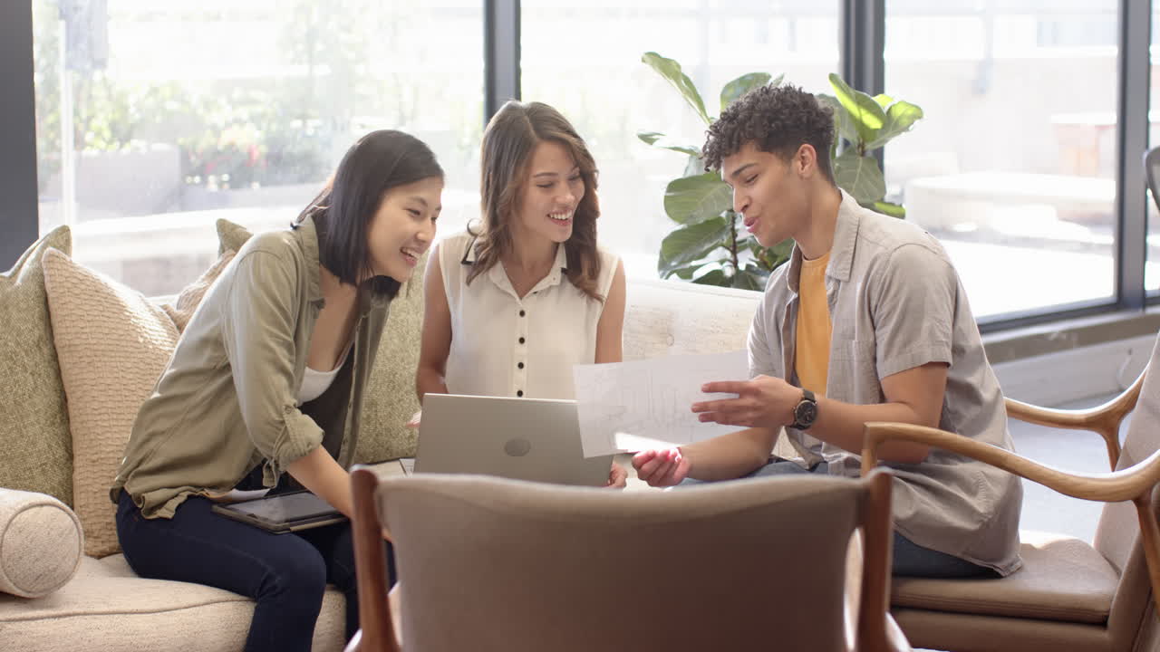 Collaborating on interior design project, multiracial team reviewing plans with laptop, at office