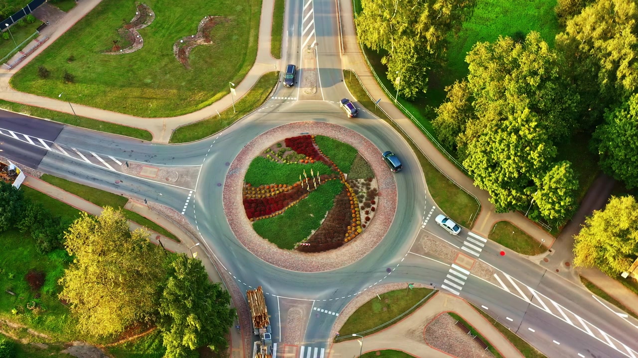Truck transporting logs drive on roundabout on sunny summer evening, aerial top view