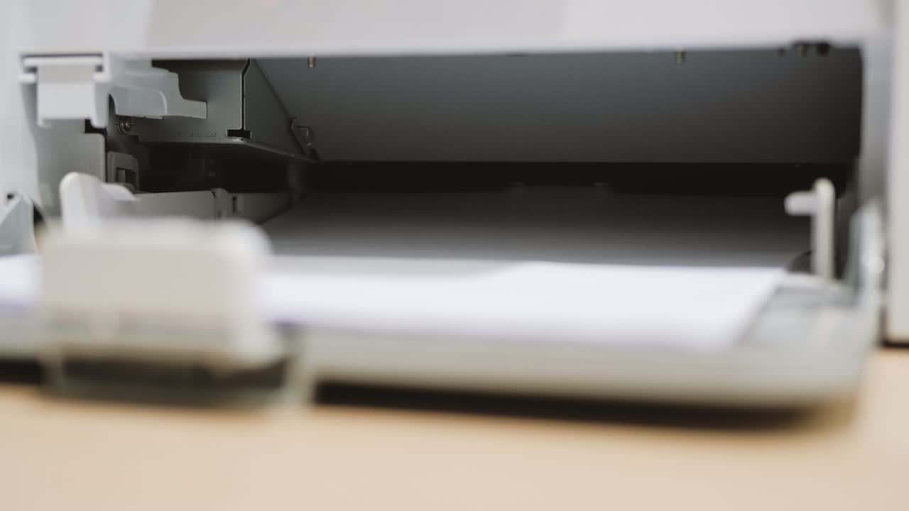 Printing document paper with laser printer close up. Laser printer at work in office or home.