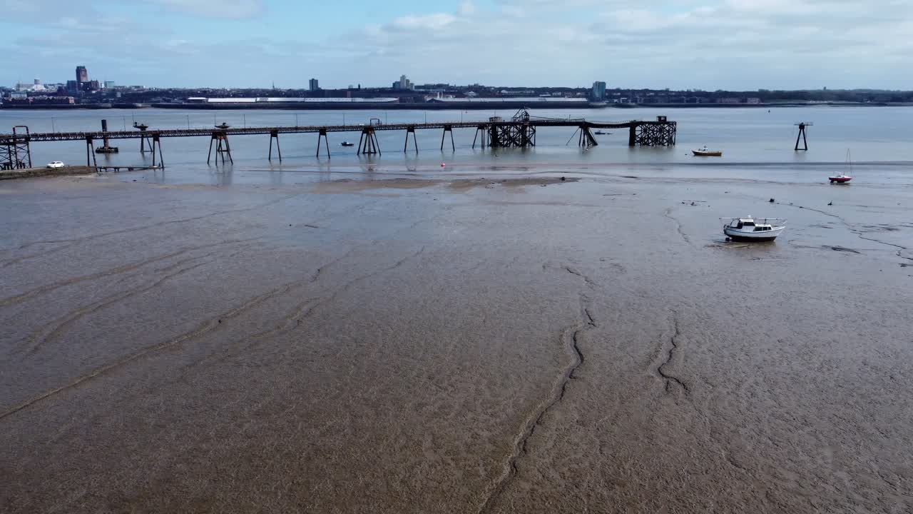 Piccola barca da pesca, vista aerea con movimento all'indietro e a sinistra di un'imbarcazione incagliata sulla bassa marea fangosa della costa di Liverpool