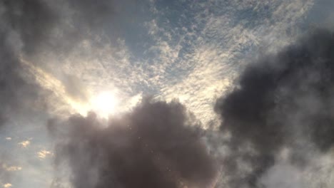 atmósfera, el sol brillando entre las nubes oscuras en el cielo azul