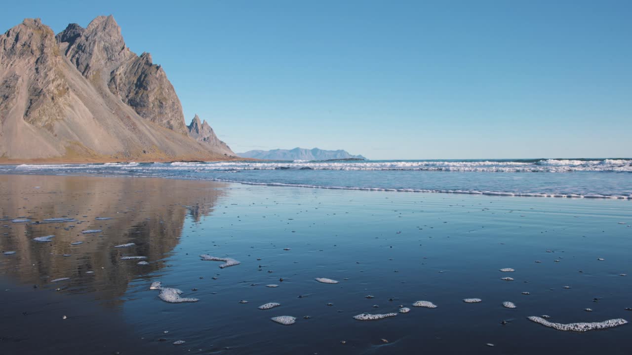 파도가 베스트라호른 산 아래의 바살트 검은 모래 해변을  ⁇ 고 있습니다.