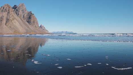 waves washing upon basaltic black sand beach below vestrahorn mountain