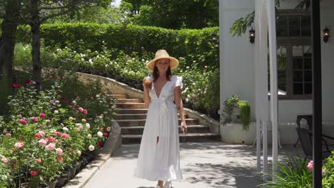 Una-Toma-Estática-De-Una-Hermosa-Joven-Caminando-Con-Un-Jugo-En-La-Mano,-Feliz-Disfrutando-De-La-Vista-Al-Jardín-Al-Aire-Libre