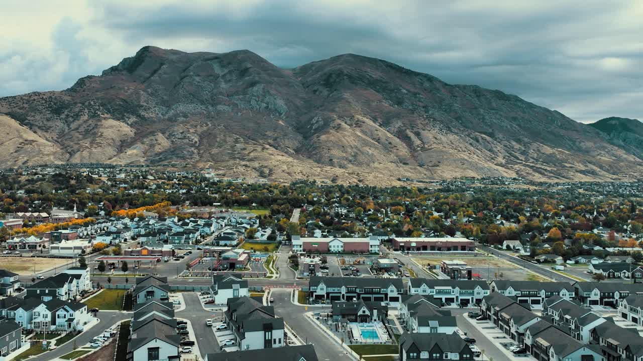 Drone video showcasing American Fork and Highland suburbs in Utah Valley with sweeping views of autumn foliage and Wasatch Front mountains. Captures peaceful residential area from above