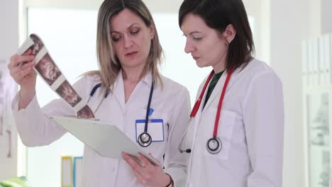 female doctors review patient files and an ultrasound scan in a clinic