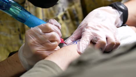 male tattooist making tattoo on hand of client