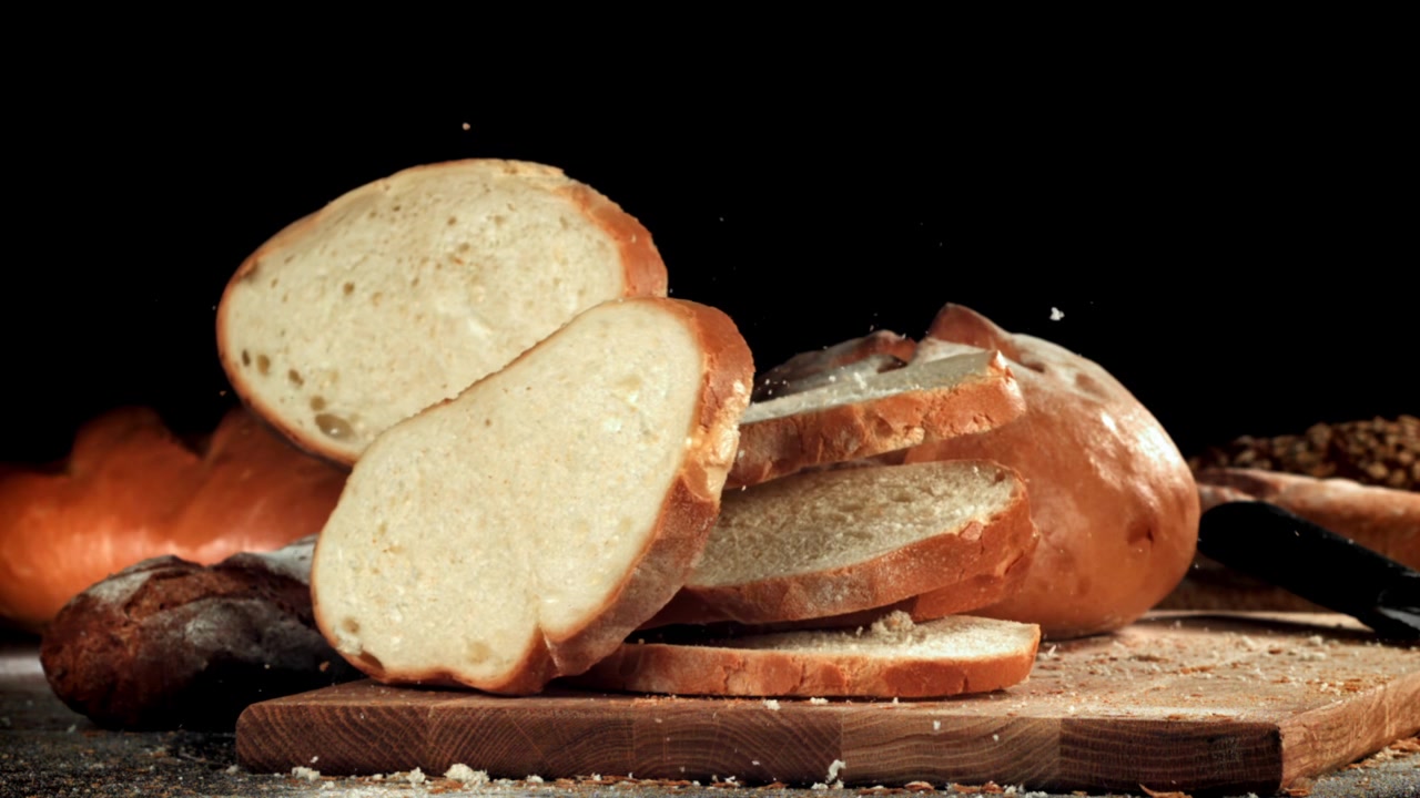 Fette di pane fresco che cadono e si impilano su un tagliere di legno
