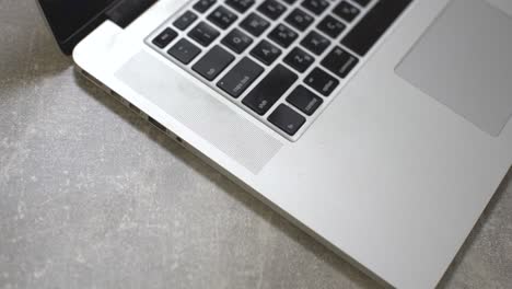 computer laptop with medical face mask, notepad and pen on top of it together with a cup of coffee on dining table. home setting. work at home concept.