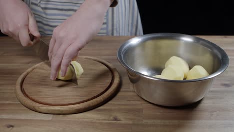 el chef saca las patatas peladas de un plato y las corta en rayas.