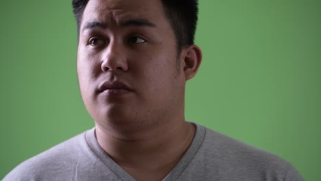 초록색 배경에 젊은 잘생긴 과체중 아시아인