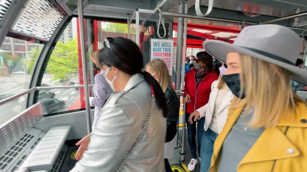 New York, USA, 8. august 2025: Gruppe kvinner iført beskyttende ansiktsmasker i offentlig transport. Tre kvinnelige passasjerer i stilige jakker står inne i en trikkekabin.