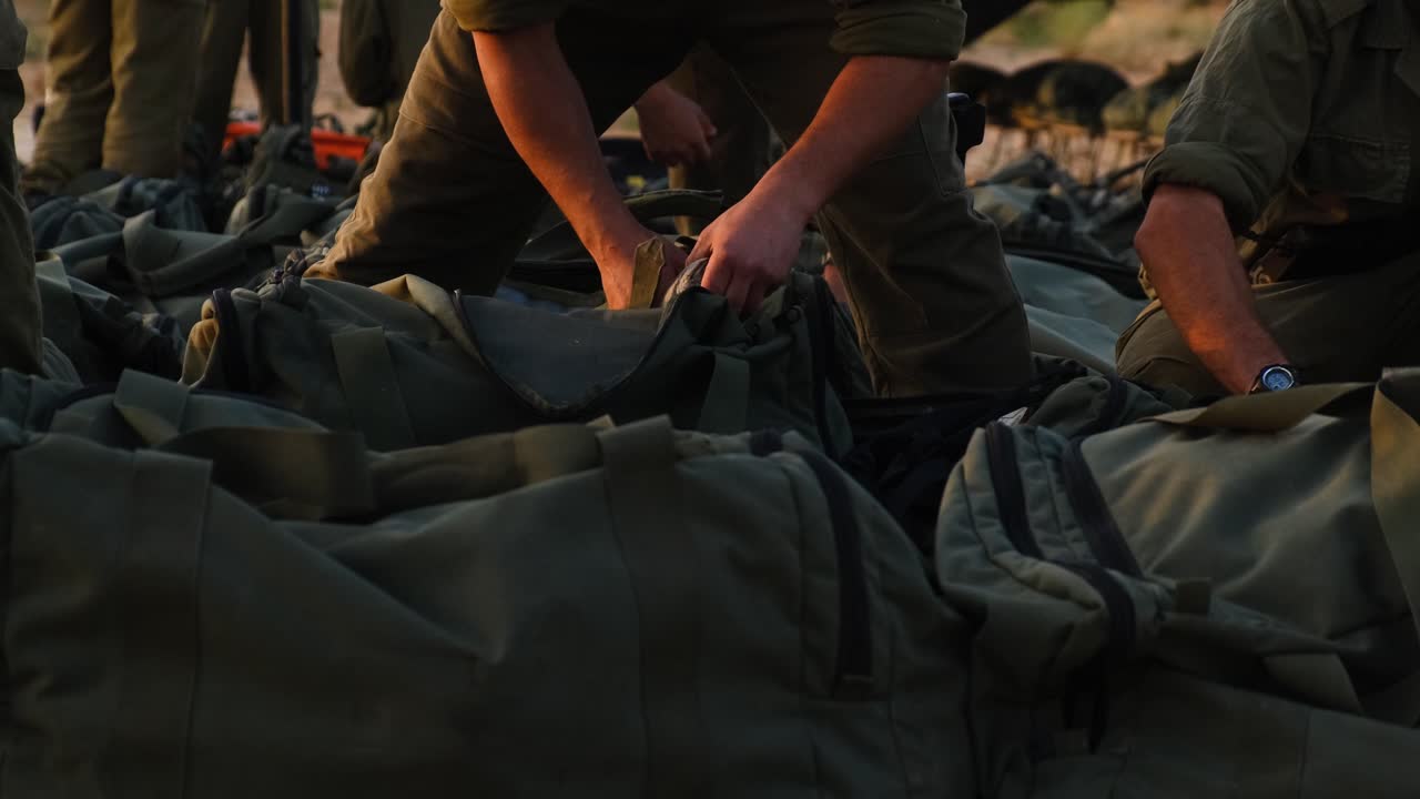 Close-up of soldiers hands and military bags with combat gear as soldiers prepare for fighting