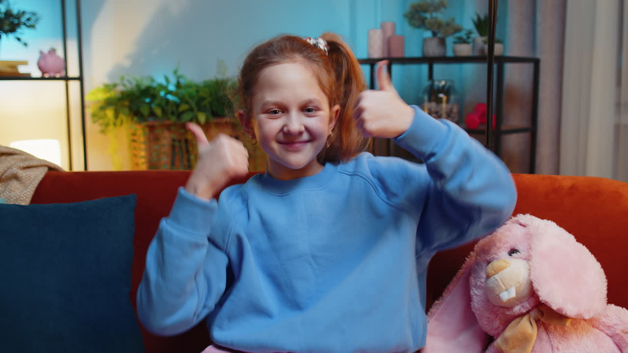 Happy child kid girl looking approvingly at camera showing thumbs up like positive sign good news