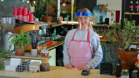 woman barista wearing face shield in cafe