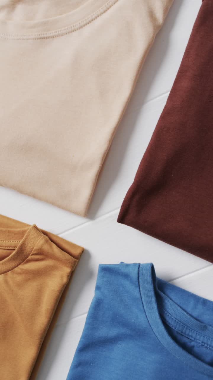 Vertical video of multi coloured t shirts with copy space on white background
