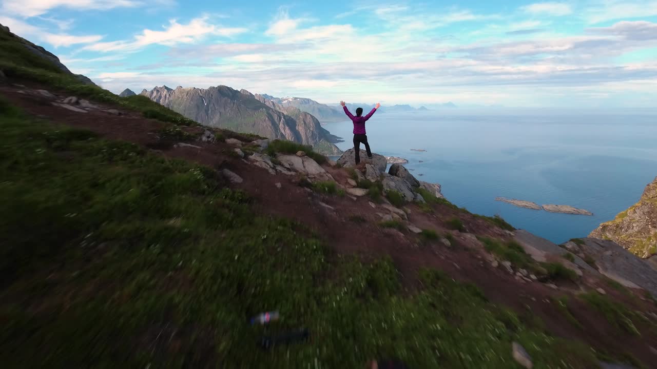 mujer excursionista de pie con las manos en alto alcanzando la cima