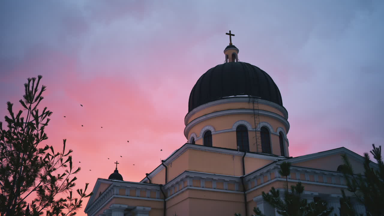 Vista esterna della Cattedrale della Natività sormontata da una croce, sullo sfondo di un cielo al tramonto rosa e azzurro tenue, Chisinau, Moldavia.