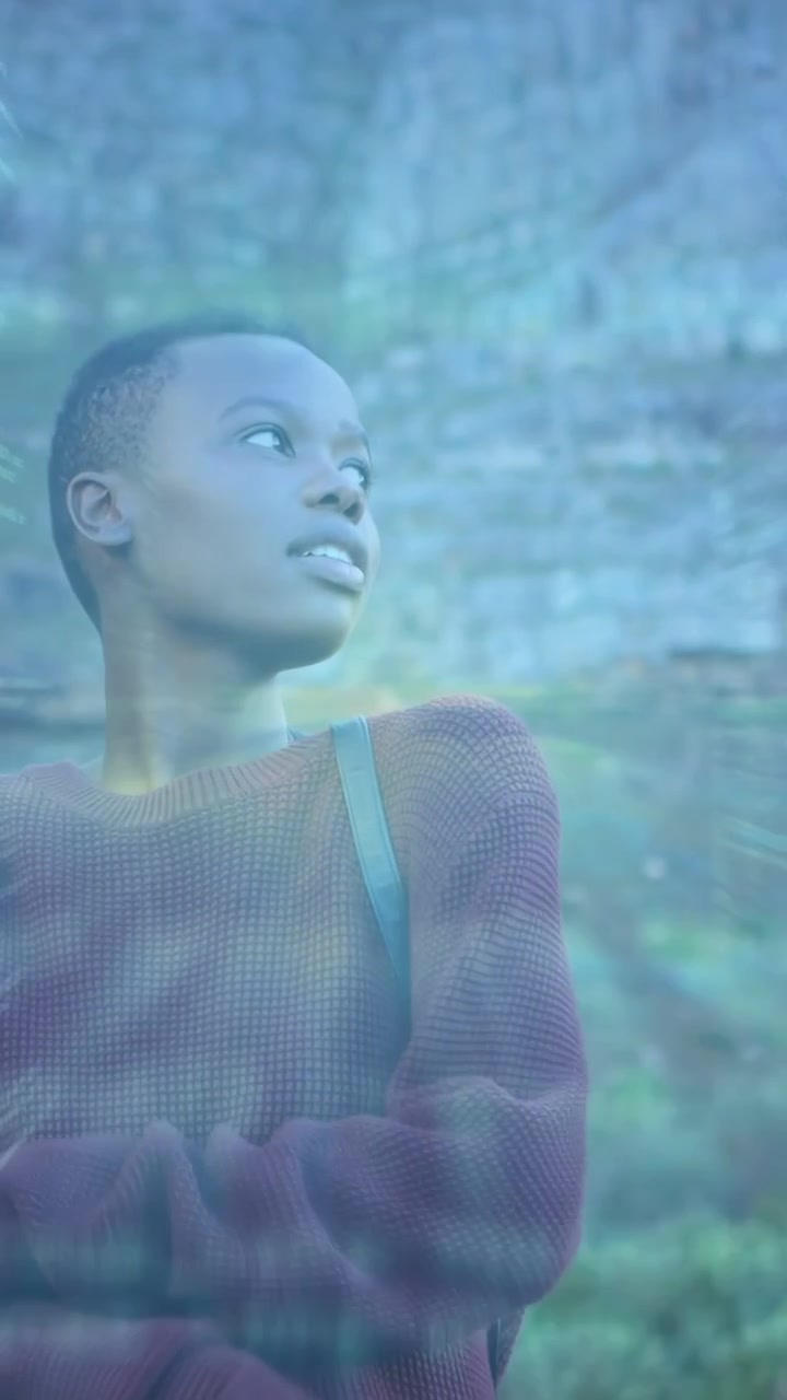 Vidéo verticale: Femme tournant la tête près d'une falaise, provoquant la convergence de code et de rayons lumineux pour la technologie.