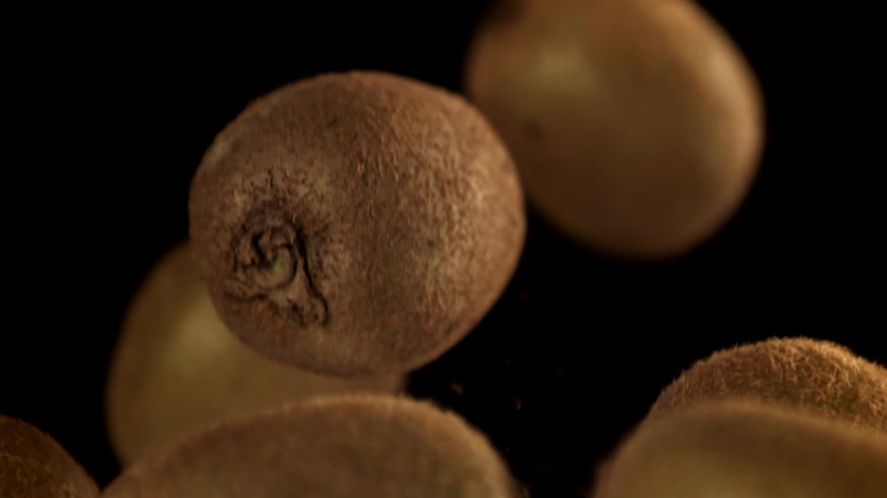 Kiwi freschi che cadono al rallentatore su sfondo nero.
