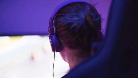 a shot of a female pro gamer from back left-side playing an online video game-1