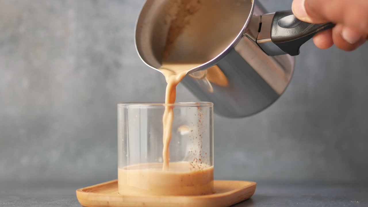 vertiendo té caliente en una taza de vidrio