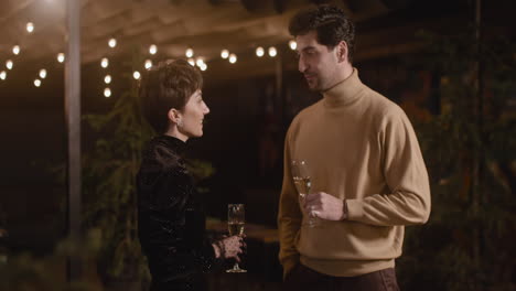 elegant woman and handsome man talking and drinking champagne at new year's eve party