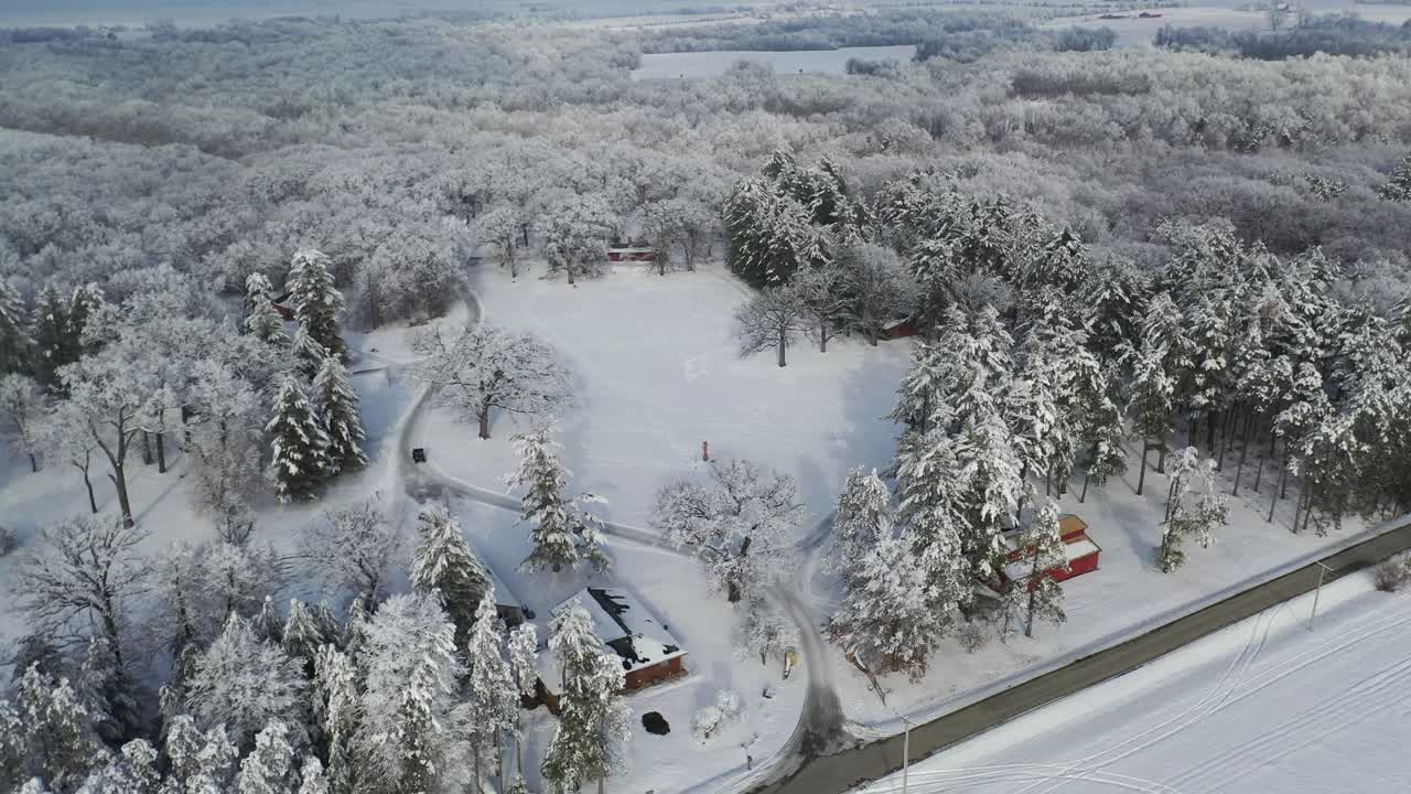 눈 덮인 겨울 숲 풍경 속에서 비포장도로를 달리는 자동차의 공중 전망