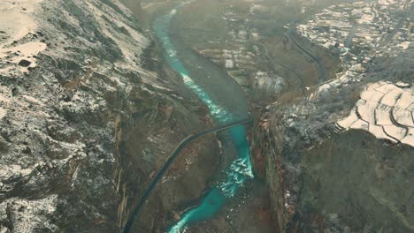 aerial panning hunza river and mountains along remote village - hunza valley