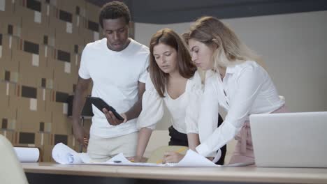 diverse coworkers meeting at table with blueprint