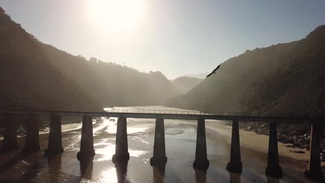 drone flight of old bridge during sunset at river mouth