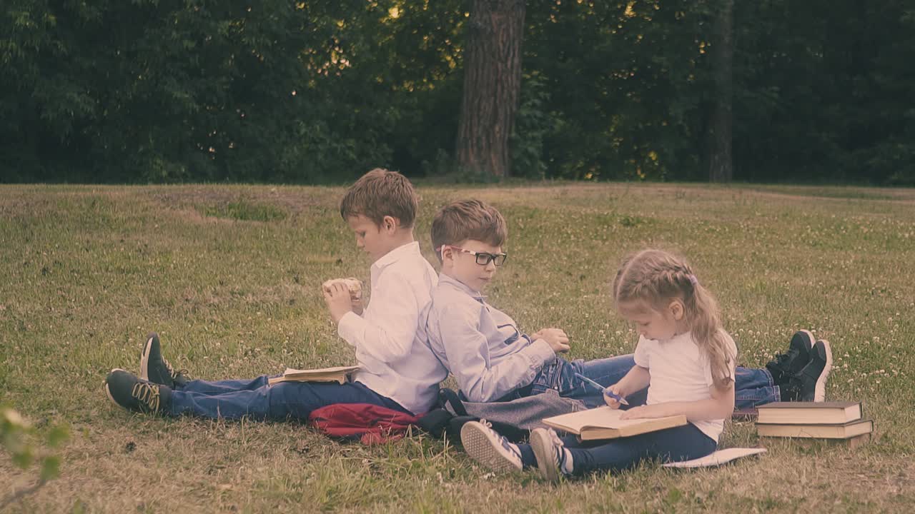 젊은 집중된 학생은 작은 여자의  ⁇ 에 앉아 책을 읽습니다.