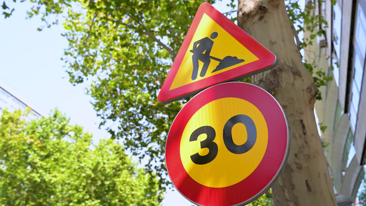 Traffic signs alert drivers to upcoming road work and a reduced speed limit of 30 km per hour. A close-up on road safety signage for construction site traffic management