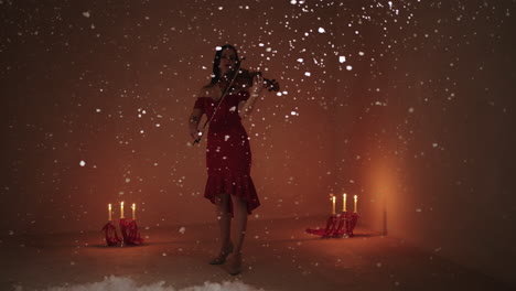 violinist in a red dress playing violin amidst falling snow