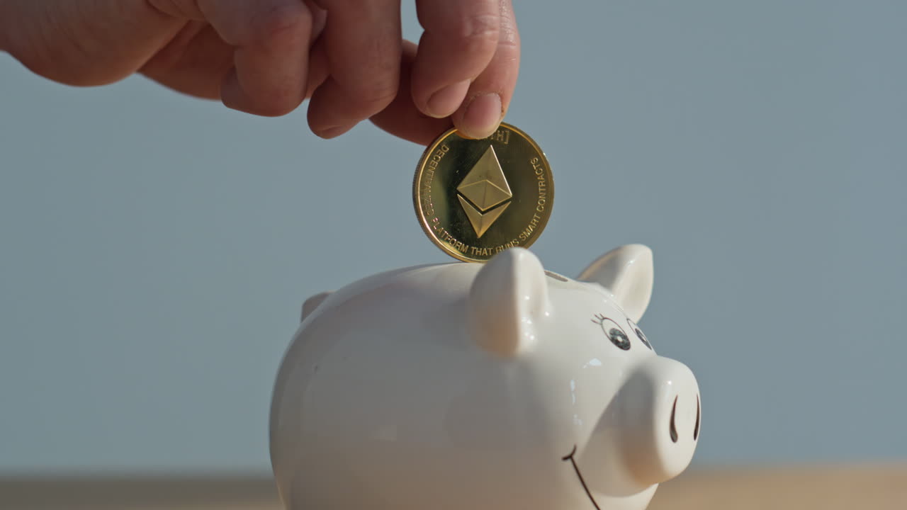 Primo piano di dita che tengono una moneta Ethereum sopra un salvadanaio bianco su sfondo grigio