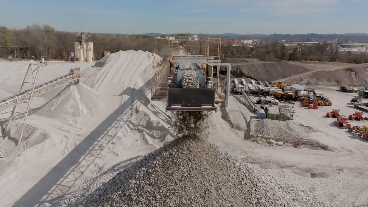 Aerial drone footage slowly moving towards fast moving rocks falling off of a conveyor belt in a quarry.
