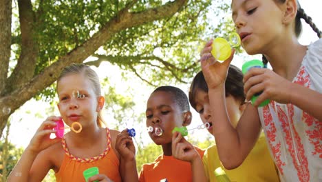 grupo de niños soplando burbujas en el parque