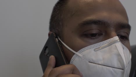 adult asian male with n95 face mask indoors talking on mobile phone