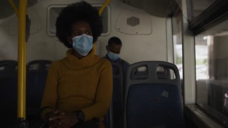 african american businesswoman with face mask sitting in bus